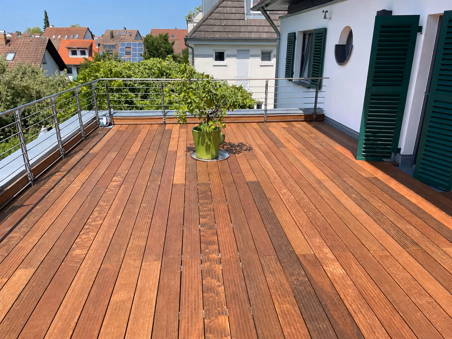 Sonnige Dachterrasse mit Holzbelag und Grünpflanze
